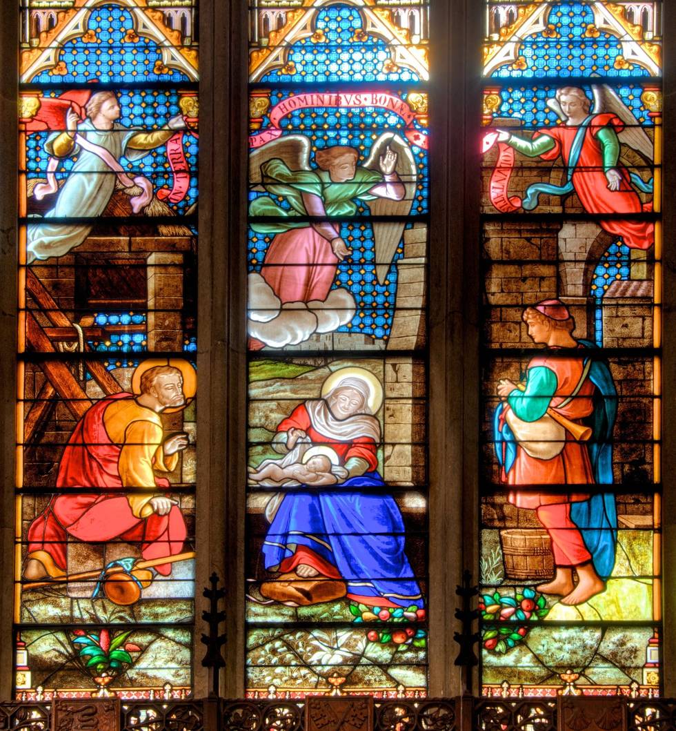 The Nativity window: Mary in deep blue with the Child, Joseph kneeling, a shepherd entering from the right.