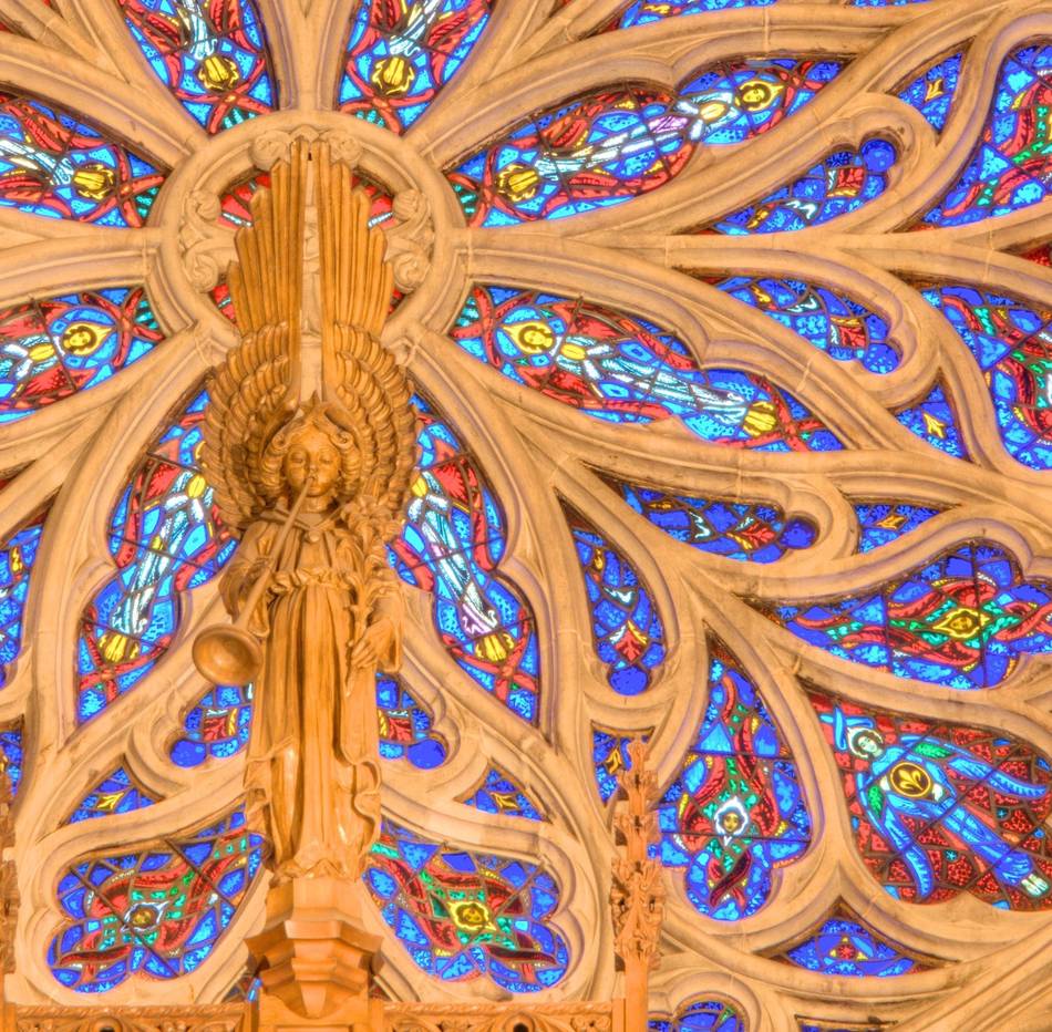 The hub of the Great Rose Window with the carved trumpeting angel of the organ case in front of it.